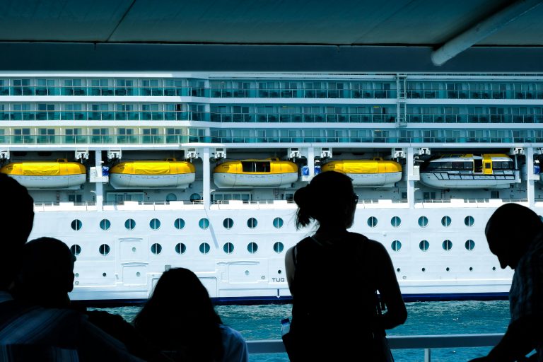 Silhouettes of people observing a large cruise ship from a dock in Türkiye.