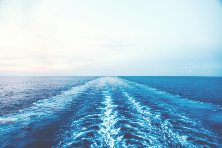 Wake of a cruise ship stretching across the open ocean to the horizon