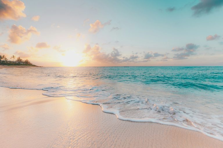 Turquoise waves rolling onto a sandy tropical beach at sunset